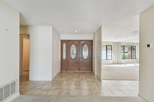 entrance foyer with light carpet and a textured ceiling