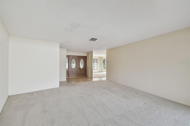 interior space featuring light colored carpet and a textured ceiling