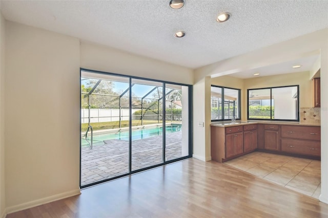 kitchen with backsplash, sink, a textured ceiling, and light wood-type flooring