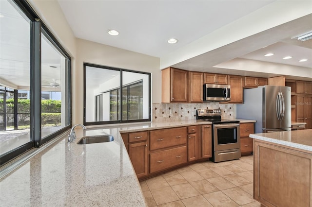 kitchen featuring sink, light stone counters, tasteful backsplash, light tile patterned floors, and appliances with stainless steel finishes