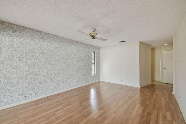 unfurnished room with ceiling fan, a textured ceiling, and light hardwood / wood-style flooring