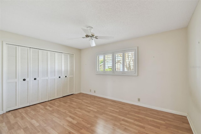 unfurnished bedroom with ceiling fan, a textured ceiling, light wood-type flooring, and a closet