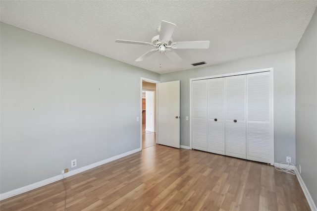 unfurnished bedroom featuring ceiling fan, a textured ceiling, light wood-type flooring, and a closet