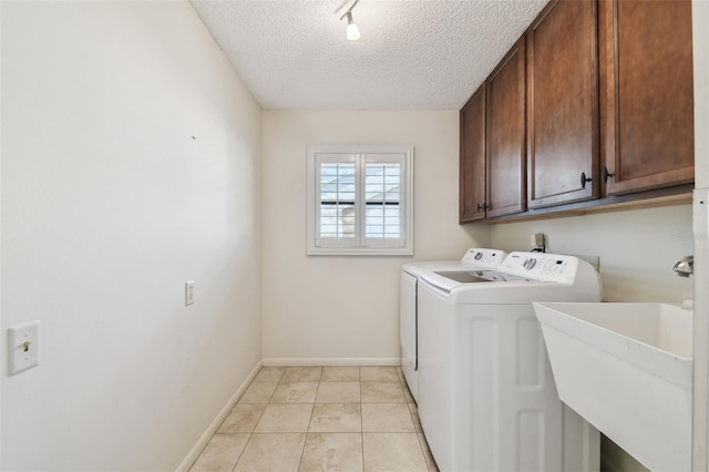 washroom featuring sink, light tile patterned floors, washer and clothes dryer, cabinets, and a textured ceiling