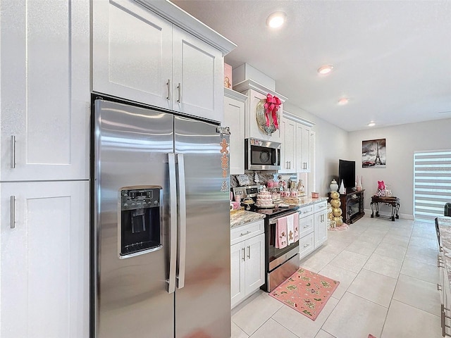 kitchen with decorative backsplash, light stone countertops, light tile patterned floors, white cabinetry, and stainless steel appliances