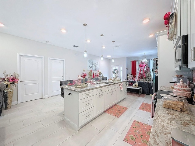 kitchen with white cabinetry, sink, stainless steel appliances, an island with sink, and pendant lighting