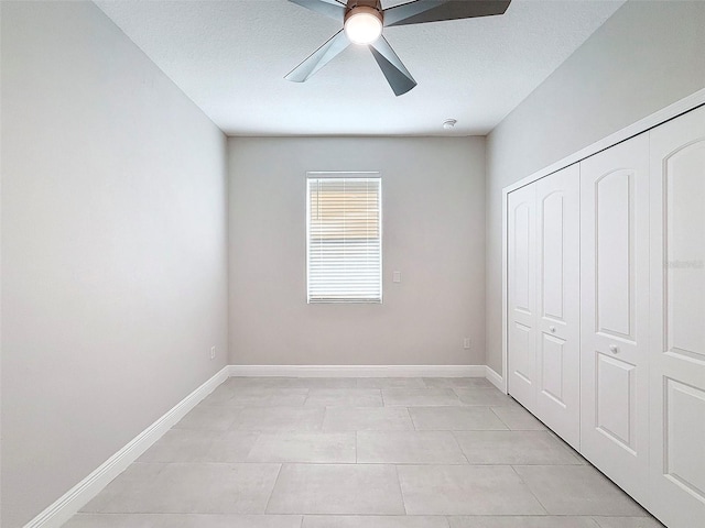 unfurnished bedroom featuring ceiling fan, a closet, light tile patterned flooring, and a textured ceiling