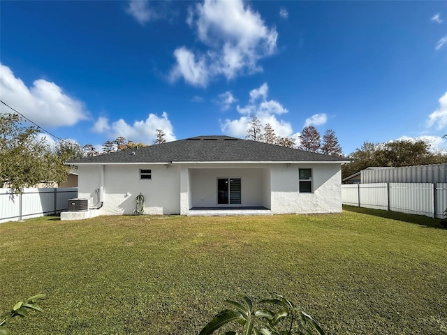 back of property with central AC unit and a lawn