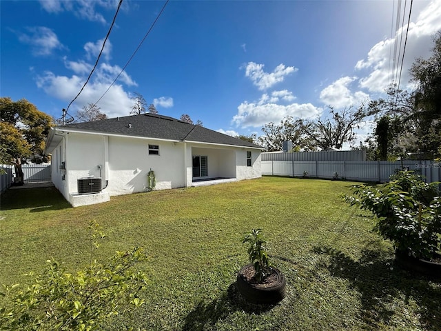 back of house with central AC unit and a lawn