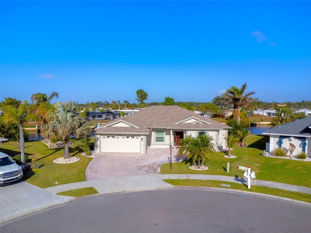 view of front of property featuring a front yard, a water view, and a garage