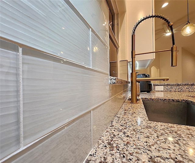 room details featuring stone countertops, decorative light fixtures, and a sink