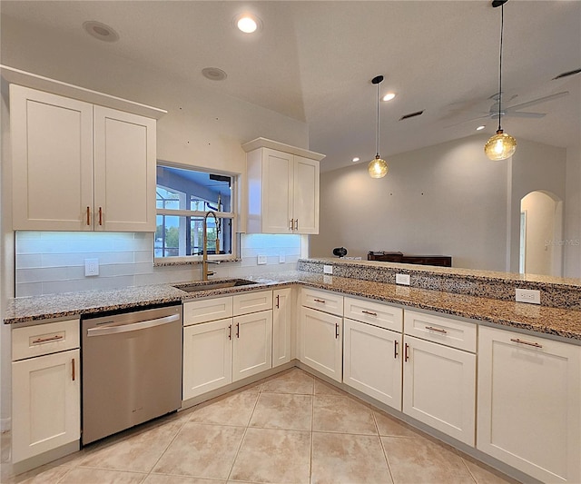 kitchen featuring decorative light fixtures, backsplash, stainless steel dishwasher, white cabinetry, and light stone countertops