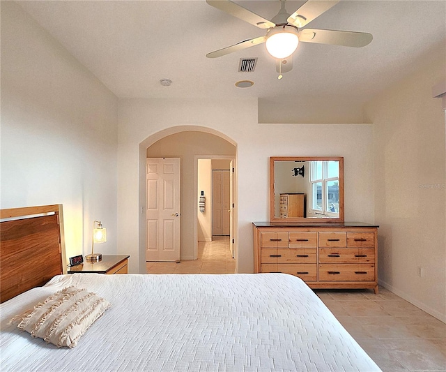 bedroom featuring light tile patterned floors, baseboards, visible vents, arched walkways, and a ceiling fan