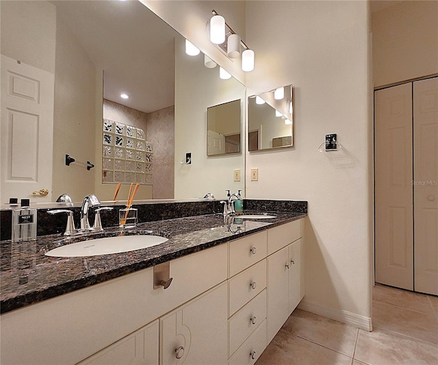 bathroom with baseboards, double vanity, a sink, and tile patterned floors