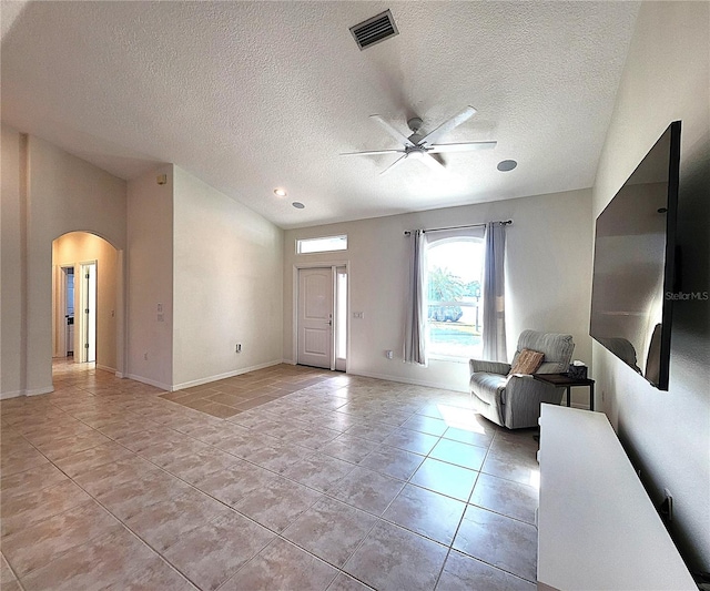 foyer featuring light tile patterned floors, baseboards, visible vents, arched walkways, and a ceiling fan