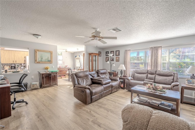 living room featuring a textured ceiling, light hardwood / wood-style flooring, and ceiling fan