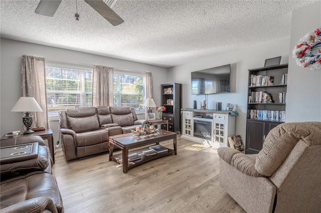 living room with ceiling fan, a textured ceiling, and light hardwood / wood-style flooring