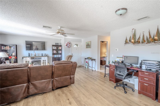 living room featuring a textured ceiling, light hardwood / wood-style floors, and ceiling fan