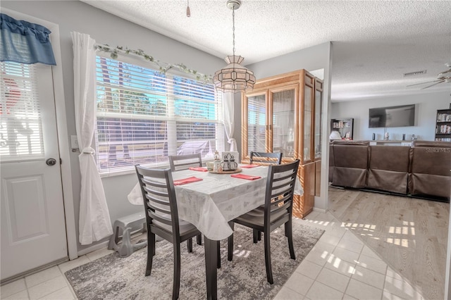 tiled dining room with ceiling fan and a textured ceiling