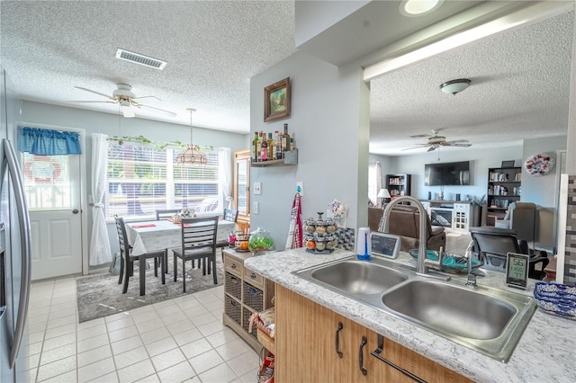 kitchen featuring pendant lighting, sink, light tile patterned floors, a textured ceiling, and stainless steel fridge with ice dispenser