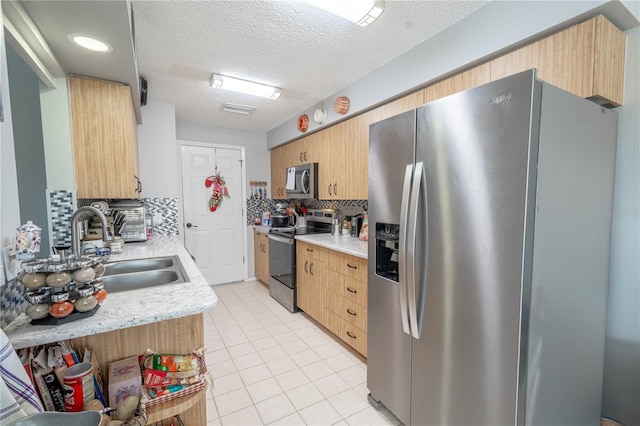 kitchen with tasteful backsplash, a textured ceiling, stainless steel appliances, sink, and light tile patterned flooring