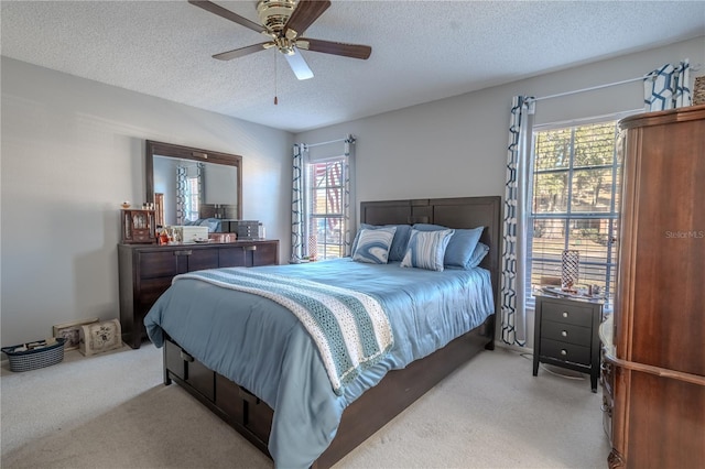 bedroom featuring a textured ceiling, ceiling fan, and light carpet