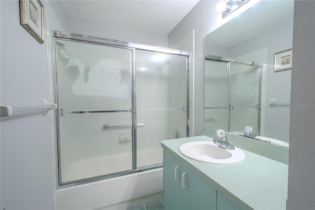 bathroom with vanity, bath / shower combo with glass door, and a textured ceiling