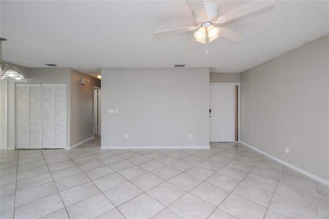 unfurnished room featuring light tile patterned floors and ceiling fan with notable chandelier