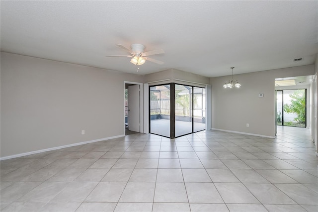 tiled empty room featuring a textured ceiling, plenty of natural light, and ceiling fan with notable chandelier