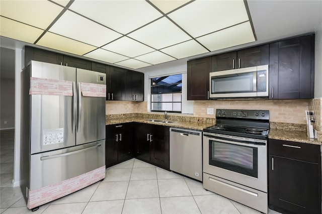 kitchen featuring stone counters, sink, stainless steel appliances, backsplash, and light tile patterned flooring