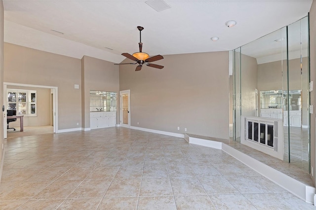 unfurnished living room featuring ceiling fan, light tile patterned floors, and a high ceiling