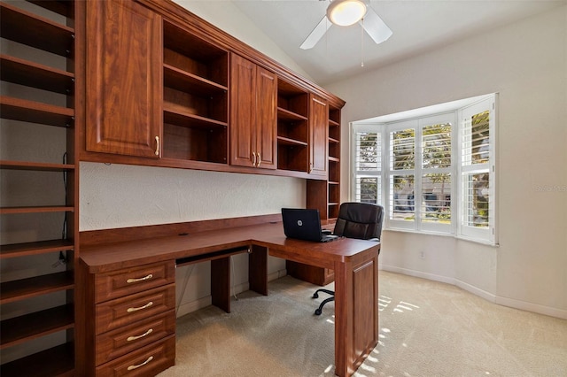 carpeted home office with ceiling fan, built in desk, and lofted ceiling