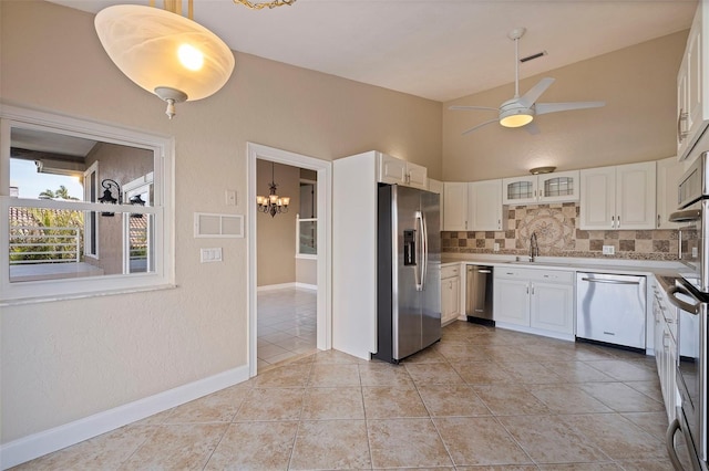 kitchen featuring stainless steel appliances, light tile patterned floors, backsplash, white cabinets, and ceiling fan with notable chandelier