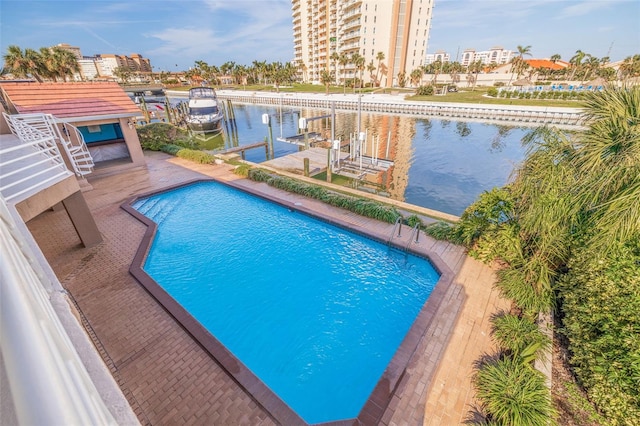 view of swimming pool with a boat dock, a patio area, and a water view