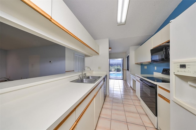 kitchen with sink, light tile patterned flooring, a textured ceiling, white appliances, and white cabinets