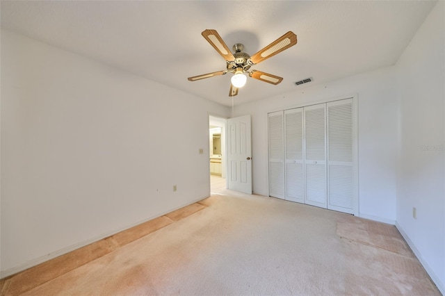 unfurnished bedroom featuring ceiling fan, a closet, and light colored carpet