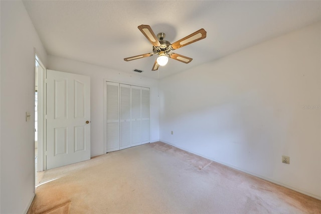 unfurnished bedroom with ceiling fan, a closet, and light carpet