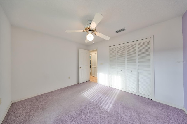 unfurnished bedroom with light carpet, a closet, and ceiling fan