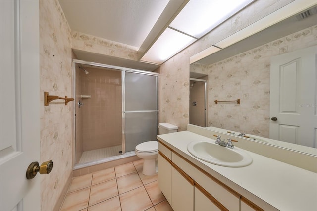 bathroom featuring tile patterned flooring, vanity, toilet, and a shower with shower door