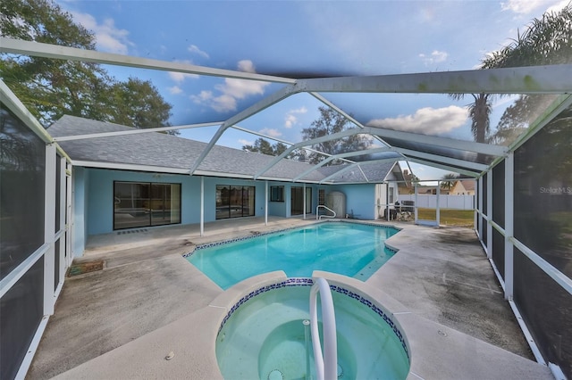 view of pool featuring glass enclosure, an in ground hot tub, and a patio