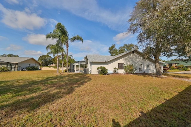 view of side of home with glass enclosure and a lawn