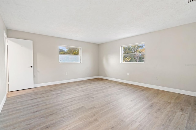 unfurnished room featuring plenty of natural light, light hardwood / wood-style floors, and a textured ceiling