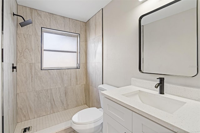 bathroom with vanity, toilet, and tiled shower