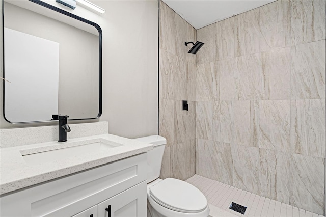 bathroom featuring tiled shower, vanity, and toilet