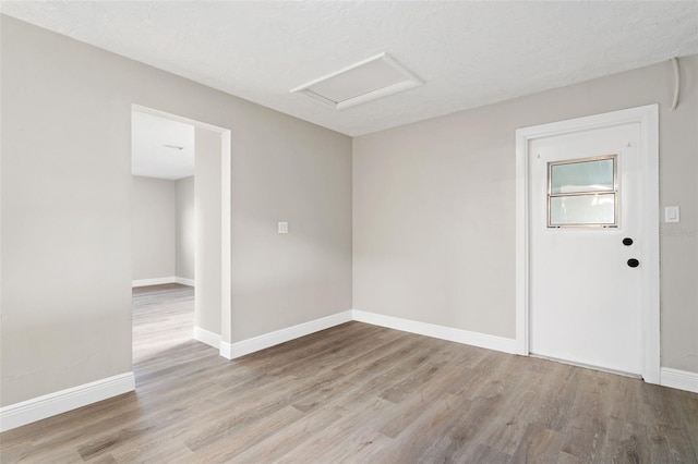 unfurnished room featuring light wood-type flooring and a textured ceiling