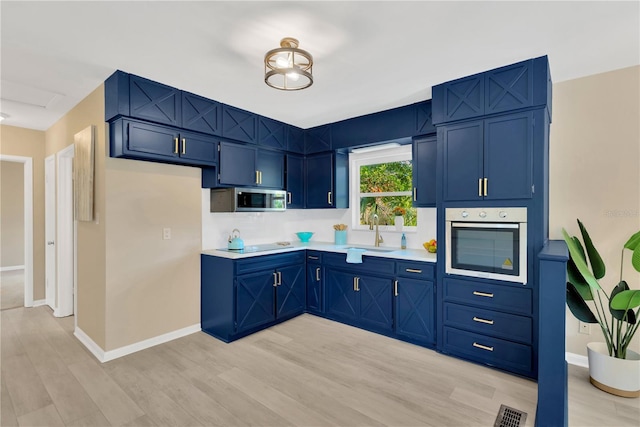 kitchen featuring sink, stainless steel appliances, light wood-type flooring, and blue cabinets