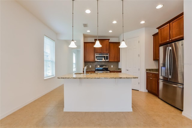 kitchen featuring hanging light fixtures, a breakfast bar, stainless steel appliances, and a kitchen island with sink