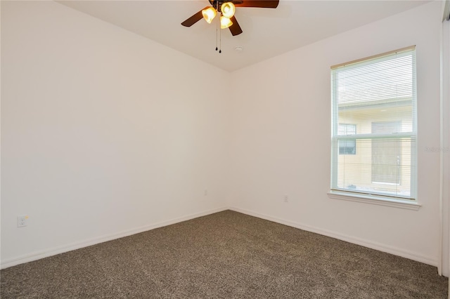 spare room with ceiling fan, a healthy amount of sunlight, and dark carpet