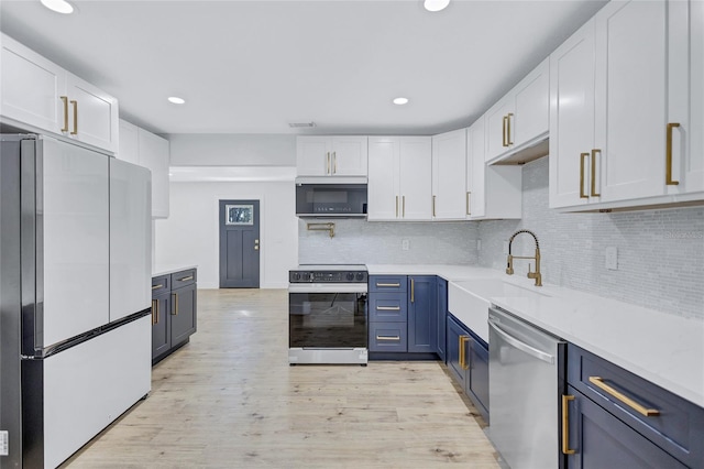 kitchen with appliances with stainless steel finishes, tasteful backsplash, white cabinetry, blue cabinetry, and light wood-type flooring