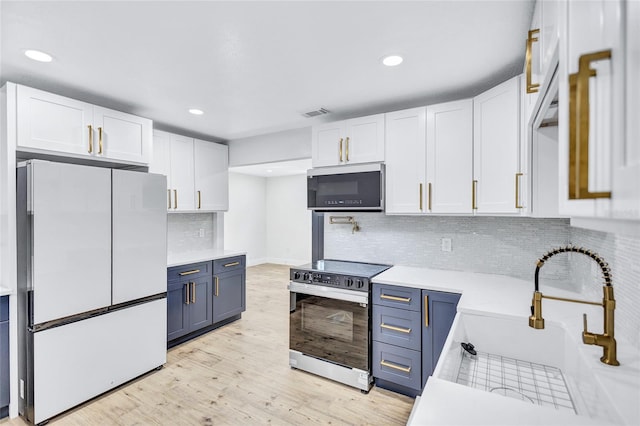 kitchen featuring white refrigerator, white cabinets, blue cabinets, and electric range